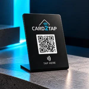Black Card2Tap NFC stand with the Card2Tap logo, a QR code and a “Tap here” NFC symbol, on a stone counter
