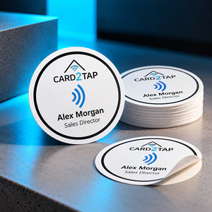 Round white Card2Tap NFC label stickers with the Card2Tap logo and Alex Morgan, Sales Director: one standing, a stack and one peeling off its backing