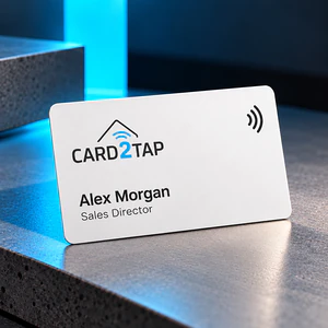White PVC Card2Tap NFC business card with the Card2Tap logo, the name Alex Morgan and the title Sales Director, on a stone ledge lit in blue
